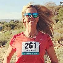Molly running through the desert with sun glasses on and smiling.